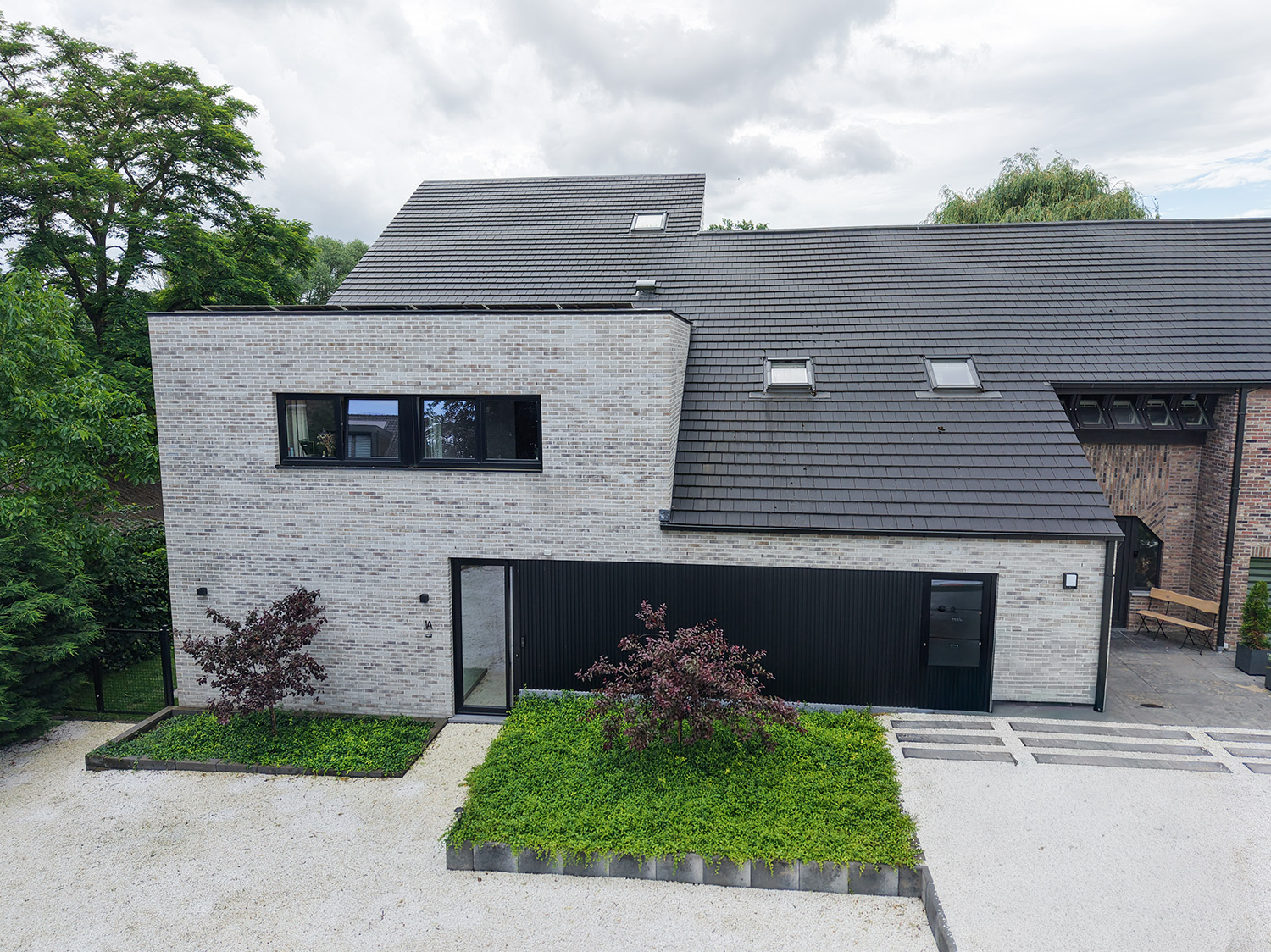 Luchtfoto van moderne aanbouw met lichte gevelsteen en zwarte gevelaccenten