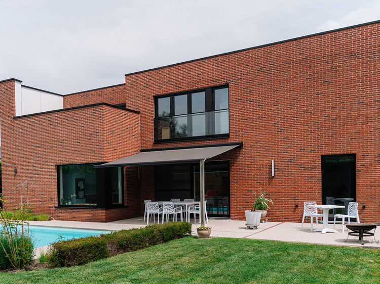 Moderne villa met rode gevelsteen gezien vanuit de tuin