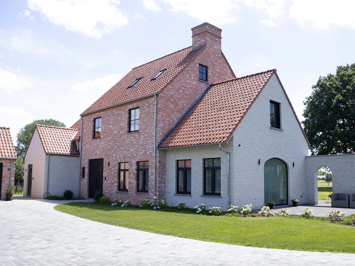Moderne landelijke houtskeletwoning in Lievegem met boograam, rode Koramic dakpan en zwart aluminium schrijnwerk