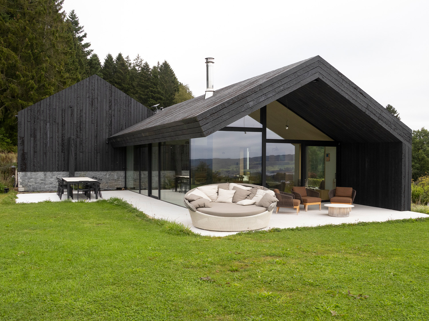 Vooraanzicht van moderne houten woning met zwarte gevel en ruim terras, realisatie door Sibomat