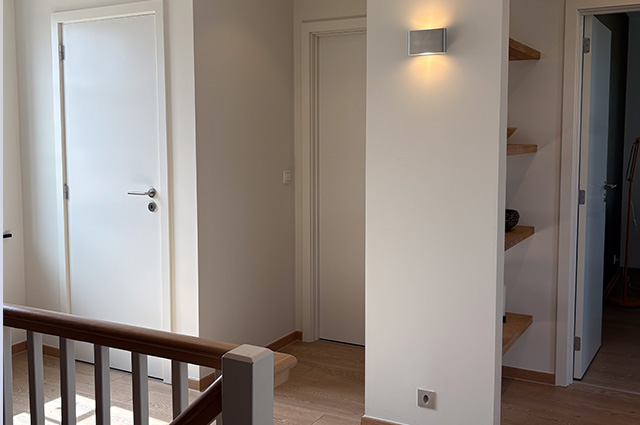 Palier à l'étage avec rampe d'escalier en bois et portes intérieures blanches dans la maison témoin Sibomat à Bierges