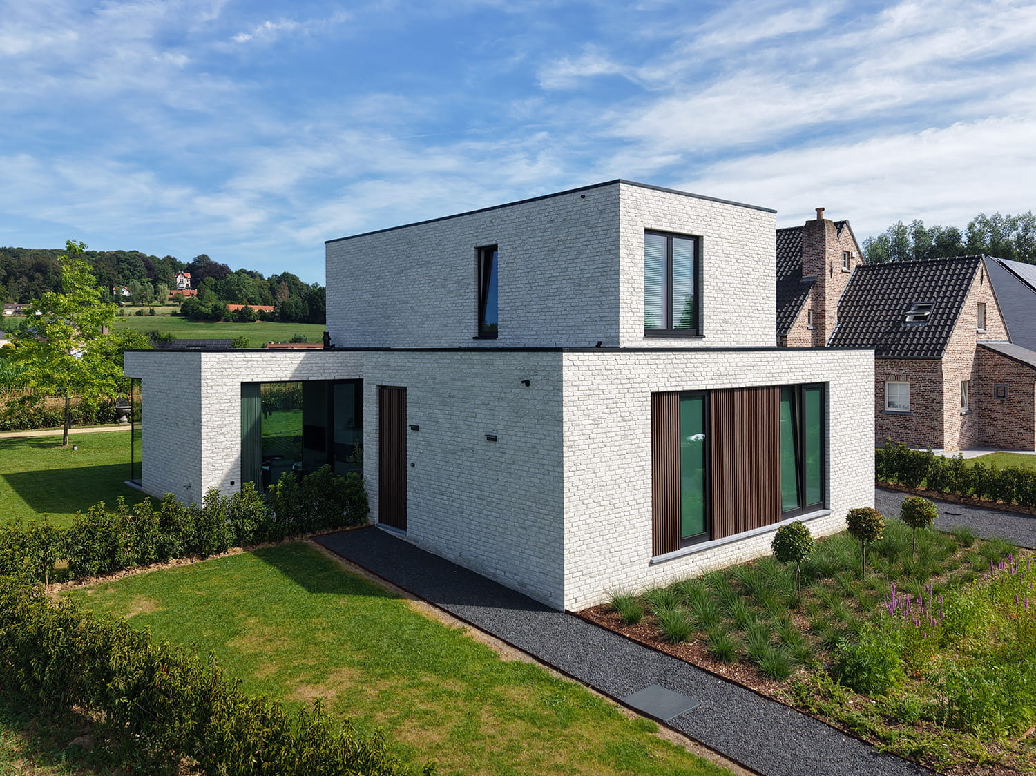 Moderne woning in Ronse met witte gevelsteen, zwarte raamprofielen en warme houtaccenten