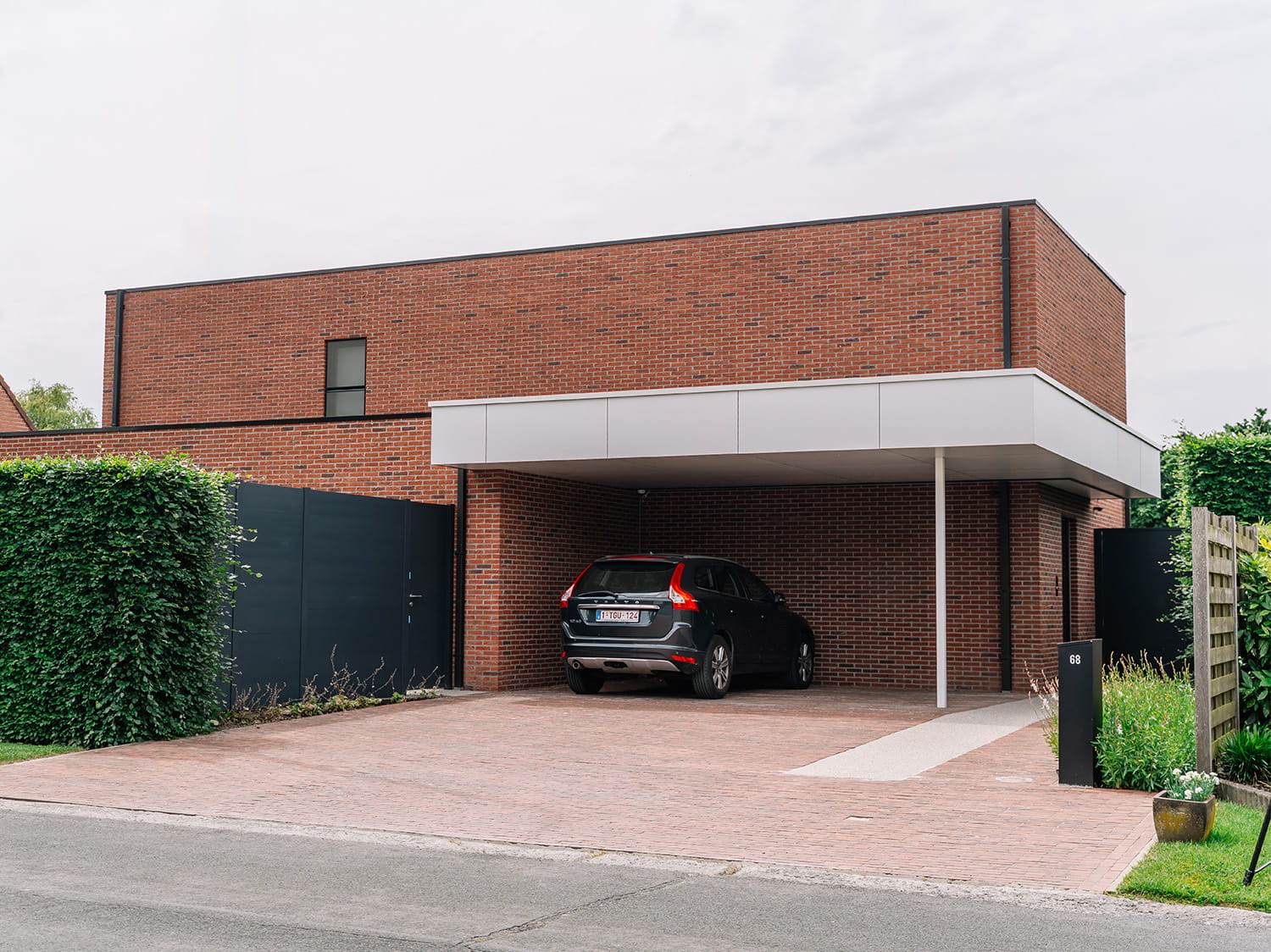 Voorgevel van moderne villa met rode gevelsteen en geïntegreerde carport