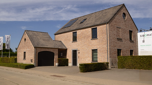 Vue de face de la maison témoin Sibomat à Bierges, avec garage et panneaux solaires